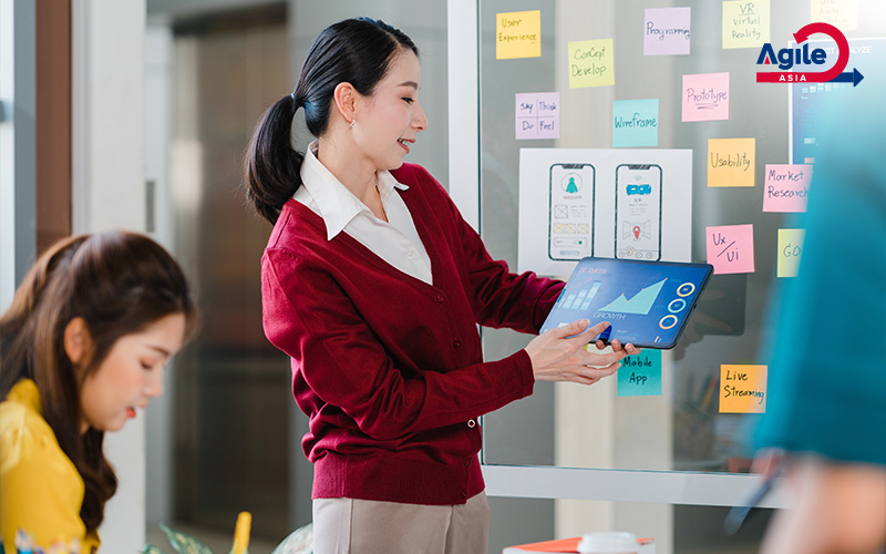 Woman presenting data on a tablet during an Agile meeting.